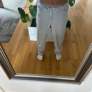 Ljusgrå byxor från H&M, strl 34 - Säljer ett par ljusgrå byxor från H&M i storlek 34. Byxorna har klassisk femficksdesign, raka ben och normal passform. Perfekta för en chill och stilren look. Materialet är mjukt och bekvämt, troligtvis bomullsmix.