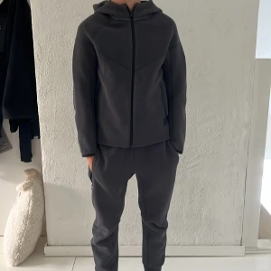  NikeTech  - Mörkgrå hoodiejacka från Nike med dragkedja framtill och huva. Och mjukisbyxor barn storlek i M