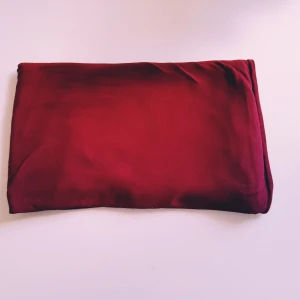 Vinröd lång sjal - Snygg och tunn vinröd halsduk i silke. Den är lång och smal, perfekt att slänga över axlarna för en stilren look. Färgen är djup och elegant, och materialet känns lyxigt och mjukt mot huden.  Lite tjockare tyg Helt skick dock tvättludd & obehandlade fläckar