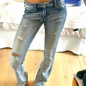Crocker lågmidjade, ljusblå, bootcut jeans - Ljusblå slitna jeans från Crocker! Jeansen har låg midja, bootcut passform, snygga slitningar och perfekt färg! Dom är verkligen coola. Har lite problem med knappen där framme som behövs fixas (så man vet) men nog inget svårt 🫶 skriv för frågor. Lite långa på mig som är 165cm! 