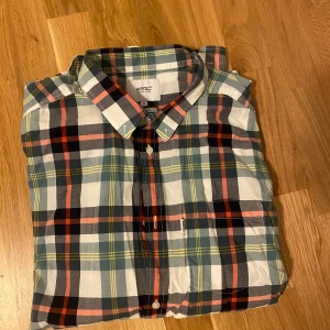 Rutig skjorta från WESC  - Snygg rutig skjorta från WESC i relaxed fit. Skjortan har långa ärmar, klassisk krage och knäppning framtill. Färgerna är en mix av blått, rött, svart, vitt och gult. Perfekt för dig som gillar en avslappnad och trendig stil.