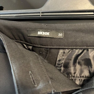 Lågmidjade svarta bik bok kostym byxor - Säljer dessa väldigt populära lågmidjade kostym byxorna ifrån bik bok! Väldigt fint skick inga defekter förutom att knappen har tappat sin färg inget man tänker på!!❣️finns även en smuts fläck på sista bilden som syns men som enkelt går att få bort! Storlek 34 och passar mig som har Xs i byxor💕🥰hör av er vid fler bilder eller frågor.  Midjemått rakt över: 37 cm midjemått runt hela: 77 cm innerbenslängd: 79 cm från midja till grenen: 20 cm 