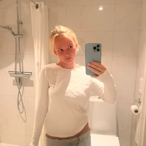 Vit långärmad tröja i bomull - En basic vit långärmad tröja i mjuk bomull. Tröjan har rund halsringning och en enkel, clean look som passar till allt. Perfekt att styla med jeans eller kjol för en chill vibe.