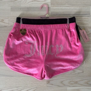 Juicy Couture shorts 2-pack i rosa och svart - Juicy Couture shorts i 2-pack, ett par i glansig rosa velour med strasslogga och ett par i svart med diskret JC-mönster. 