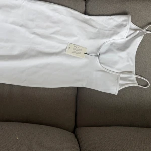 Vit  klänning  - Säljer en enkel och stilren vit klänning med smala axelband. Klänningen har en tight passform och är perfekt för sommaren. 