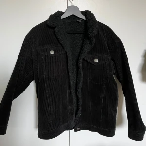 Svart manchesterjacka - Säljer en svart manchesterjacka från Monki i storlek XXS. Stor i storleken, passar perfekt på mig som brukar ha storlek s. Jackan har teddyfoder, krage och två bröstfickor med knappar. Perfekt för kyligare dagar och ger en cool, avslappnad look💗