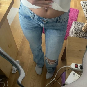 Ljusblå  jeans med bootcut - Säljer ett par jättesnygga lågmidjade ljusblå jeans med bootcut och hål vid knät. Storlek 36/S!! Tecken på användning finns, de är slitna längst ner då de varit lite långa på mig! Från H&M💕💕