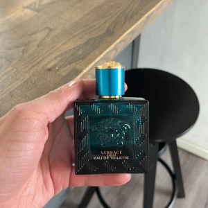 Versace Eau de Toilette herrparfym - Elegant herrparfym från Versace i en mörkgrön fyrkantig glasflaska med guld- och turkosblått lock. Flaskan har Versaces ikoniska Medusa-huvud i relief och gulddetaljer. Perfekt för dig som gillar lyxiga dofter. Denna flaska har 35 ml kvar i sig!