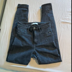 Svarta skinny jeans från Gina Tricot Molly - Svarta Molly-jeans från Gina Tricot med hög midja och skinny passform. Klassisk femficksmodell med dragkedja och knapp framtill. Perfekta basjeans som passar till det mesta.