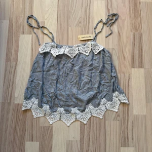 Topp med spetsdetalj - Strl xs / s. Ljusblå somrigt linne från River Island. Det har fina spets detaljer och axelbanden kan man knyta hur man vill, jätte svårt att ge rättvisa på bild! Aldrig använt prislapp kvar 