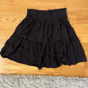 Svart volangkjol med resårmidja - En svart kortkjol med volangdetaljer. Använd fåtal gånger, säljer då den tyvärr inte kommer till användning