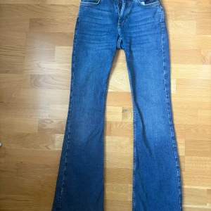 Blå bootcut jeans från Gina Tricot  - Säljer ett par blåa bootcut jeans från Gina tricot. Jeansen har normal passform, fem fickor och dragkedja med knapp framtill. Jeansen har låg midja. Perfekta för dig som gillar en tidlös jeansstil med lite utsvängda ben. Säljer endast för att de är för små. Priset kan diskuteras