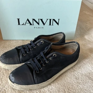 Blåa lanvin cap toe - Säljer ett par marinblå lanvin cap toe! Dessa är perfekt nu inför sommaren och otroligt sköna. De är uk 8 vilket är 42 men sitter som 43. Skicket är väl okej. Mockan mår bra och inuti skon är inget förstört, även snörena är bra. Som ni ser på bild 4 så finns en defekt på vänster sko sula insida, men inget man märker av. Det som ingår vid köp: Box, två dustbag och även skönören till båda skor som aldrig är använda 👌🏻. Vid frågor hör av er! 