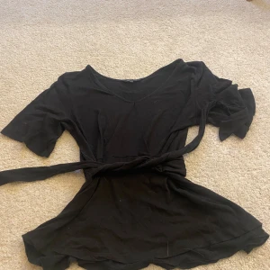 Svart omlottopp med knytband från Happy Holly - Säljer en svart omlottopp från Happy Holly i storlek 36/38 passar även Xs💞 man kan välja om man vill knyta fram eller bak! 