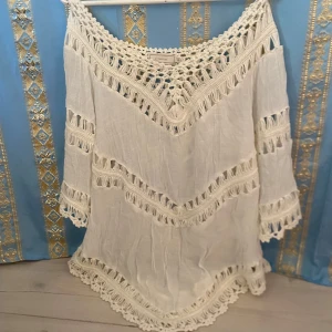 Vit boho-blus med virkade detaljer från Cream - Säljer en vit blus från Cream med vackra virkade detaljer och fransar. Blusen har trekvartsärm och lös passform, perfekt för en avslappnad och bohemisk stil. Materialet känns luftigt och lätt.