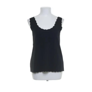 Svart linnetopp med vågig kant  - Säljer en svart topp från Laura Torelli Collection. Toppen har en snygg vågig kant både vid halsringningen och nederkanten, vilket ger en unik och stilren look. Perfekt att matcha med jeans eller kjol.