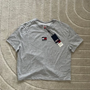 Grå t-shirt från Tommy Hilfiger - Ny grå t-shirt från Tommy Hilfiger!.                                                                  • Storlek M • Har du några frågor är det bara att skicka ett meddelande, så svarar jag så fort jag kan.☺️ Ha en fin dag!💕♻️