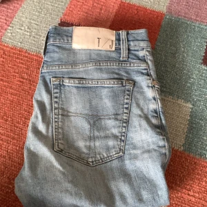 Ljusblå jeansbyxor från Tiger of Sweden - Säljer ett par ljusblå jeansbyxor från Tiger of Sweden. Klassisk femficksmodell med raka ben och normal passform. Perfekta till vardags och lätta att matcha med olika stilar. Liten defekt på patchen och ganska använda. Hör av dig om du vill fråga någonting! Byten funkar 