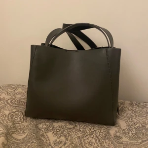 Grå väska - Grå rymlig väska från Gina Tricot mellan modellen tror jag om inte den lilla, den har ett långt band som sitter fast som du kan ha på axeln. 🌸 