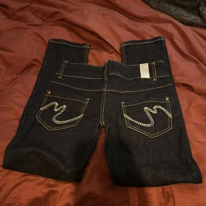 Mörkblå jeansbyxor med kontrastsömmar från Vero Moda - Säljer ett par mörkblå jeansbyxor med raka ben och kontrastsömmar. Byxorna snygga detaljer på bakfickorna. De går att göra om så de blir med bootcut modellen. De är riktigt lågmidjade med ca 80 cm i midja och 67 cm i innerben 