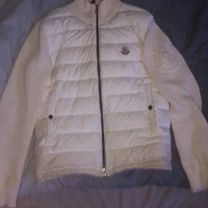 Vit Moncler cardigan med stickade ärmar - Jag säljer en snygg vit cardigan från Moncler med stickade ärmar och rygg. Scanner funkar, allt annat är också legit. Den e knappast använd och har varit väldigt sparsam och i bra skick. Hör av dig för fler frågor eller bilder. Mvh Vilde