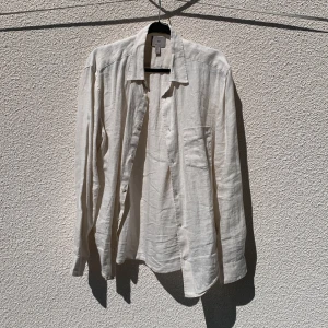 Beige linneskjorta från H&M - Säljer en stilren beige skjorta i 100% linne från H&M. Skjortan har klassisk krage, lång ärm och knäppning framtill. Bröstficka på vänster sida. Storlek L.