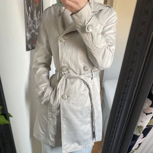 Trenchcoat - Kortare trenchcoat med snygg passform. Använd men i bra skick!