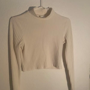Vit croppad tröja - Säljer en vit croppad tröja med lång ärm. Toppen har en tight passform och är perfekt för att styla med höga jeans eller kjol. Enkel och stilren design som passar till många olika outfits.🤍