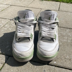 Nike Air Jordan 4 seafoam Olive green - Säljer ett par Nike Air Jordan 4 Retro i vitt med gröna och svarta detaljer. Helt perfekt skick, liten  crease men inget som man lägger märke till när man använder de. Perfekta för dig som gillar streetwear och vill sticka ut med en ikonisk sneaker. Perfekt nu för sommaren med somriga färger. Har du några frågor är det bara att kontakta. Pris kan diskuteras vid snabbt köp.
