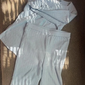 Ljusblå ribbad kofta från SHEIN - Säljer en ljusblå ribbad kofta från SHEIN i storlek XS. Koftan har lång ärm, rund halsringning och dragkedja framtill. Materialet är mjukt och stretchigt, perfekt för en chill look. Matchande shorts ingår ej, endast koftan säljs.