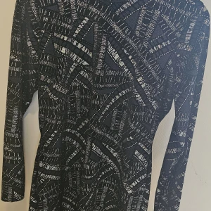 Glittrig svart klänning NLY Trend XL - Snygg svart kortklänning från NLY Trend i storlek XL. Klänningen har ett glittrigt mönster i silver, långärmad modell och figurnära passform. Perfekt för dig som vill sticka ut med coola detaljer och glansiga inslag. Passar för dig som har storlek M och L också.