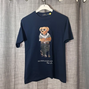 Marinblå t-shirt med Polo Bear från Ralph Lauren - Tja! Säljer en as fet mörkblå polobear tshirt | Skick 9,7/10 som ny! | Mitt pris 449kr | Han på bilden är 188cm, passar bäst för dig under 185 | Nypris runt 1500kr | hör av dig vid några funderingar eller frågor 