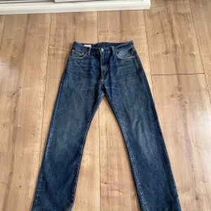 Levi's 551 blå jeans W30 L30 - Klassiska blå Levi's 551 jeans med rak passform och fem fickor. Jeansen har en snygg mörkblå tvätt och detaljer i kopparfärgad metall. Tillverkade i slitstarkt denim med läderpatch bak i midjan. Helt okej skick men inga defekter. Hör av dig vid fler frågor mvh Theo!