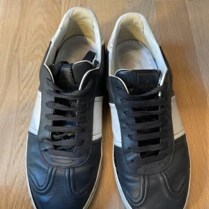 Svarta och vita Valentino sneakers - Säljer ett par blå och vita Valentino flycrews efter som dom är för små för mig. Dom har gått igenom mycket 5 nitar saknas och trådarna som håller ihop sulan har gått upp och behöver lagas kolla bilderna. Det har också tillsatt en läder där bak för det hade blivit upprivet.skick 6/10 box eller dustbag förekommer inte