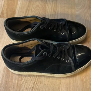 Svarta sneakers med lackad tå - Säljer nu mina Lanvins i svart storlek uk6 dom är rätt slitna trådarna på skorna har gått upp på ett ställe kolla bilden men annars okej skick box eller dustbag förekommer inte