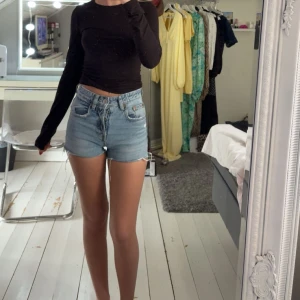 Ljusblå jeansshorts - Säljer ett par klassiska ljusblå jeansshorts från Zara. Shortsen har knappar framtill. Perfekta för sommaren och enkla att matcha med olika toppar.