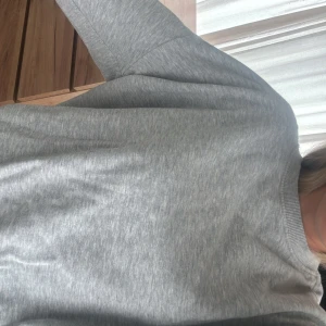 Grå hoodie i bomull - Säljer en enkel och stilren grå hoodie med huva och långa ärmar. Tröjan har en klassisk passform och är tillverkad i mjukt bomullsmaterial. Perfekt för en avslappnad look.