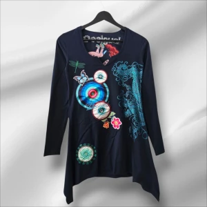 Desigual långärmad blus med tryck - Unik långärmad blus från Desigual i mörkblått med färgstarka tryck och broderier, bland annat cirklar, fjäril, trollslända och blommor. V-ringad hals med cool detalj och asymmetrisk nederkant. Perfekt för dig som gillar statement-plagg och kreativ stil.