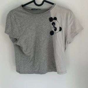 Grå och vit t-shirt med panda från FB Sister - Säljer en söt t-shirt från FB Sister i grått och vitt med en panda-illustration på bröstet. T-shirten har korta ärmar och är i mjuk bomull, perfekt för en avslappnad stil.