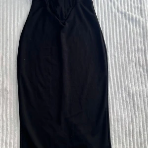 Svart långklänning med smala axelband - Säljer en svart långklänning med smala axelband och figurnära passform. Klänningen har en markerad midja och en stilren, minimalistisk design som ger en elegant siluett. Perfekt för dig som gillar klassiska och tidlösa plagg.