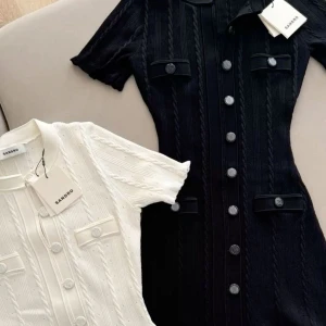 Kortärmad klänning med knappar från Sandro - Två snygga kortärmade klänningar från Sandro, en i svart och en i vit. Båda har dekorativa knappar framtill, krage och fickdetaljer på bröstet. Klänningarna har en klassisk, figurnära passform och är tillverkade i ett stickat material. Säljer dock bara den svarta för tillfället och kan skicka fler bilder vid önskemål.