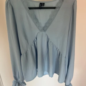 Ljusblå blus med spetsdetalj - Säljer en ljusblå blus från veromoda med v-ringning och spetsdetalj längs urringningen. Blusen har långa ärmar med resår vid ärmslut och en lös passform som ger ett luftigt intryck. Använd ett fåtal gånger! Storlek S🤍