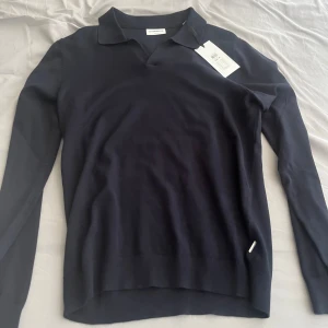 Mörkblå pikétröja från Lindbergh - Säljer en stilren mörkblå pikétröja från Lindbergh i slim fit-modell. Tröjan har klassisk krage och är tillverkad i ett mjukt material som passar perfekt till många tillfällen. Enkel och tidlös design.