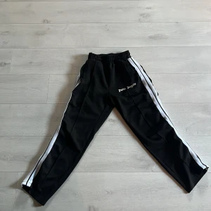 Svarta från Palm Angels - Svarta från Palm Angels med vita ränder längs sidorna och logga broderad på vänster. Pris 450! storlek M. Hör av vid frågor!