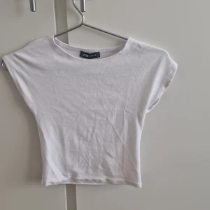 Vit croppad topp - Säljer en stilren vit croppad topp från FB Sister/newyorker. Toppen har en enkel design med korta ärmar och rund halsringning. Aldrig använd, nypris 79 kr