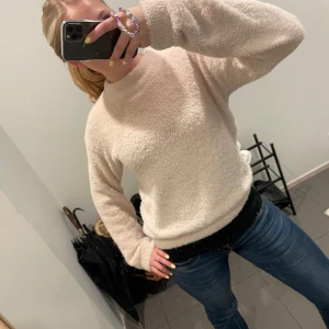 Beige fluffig tröja från H&M - Mysig och fluffig beige tröja från H&M. Perfekt för kyliga dagar med sin mjuka och varma känsla. Tröjan har långa ärmar och en rund halsringning. Enkelt att matcha med jeans eller kjol för en avslappnad look.