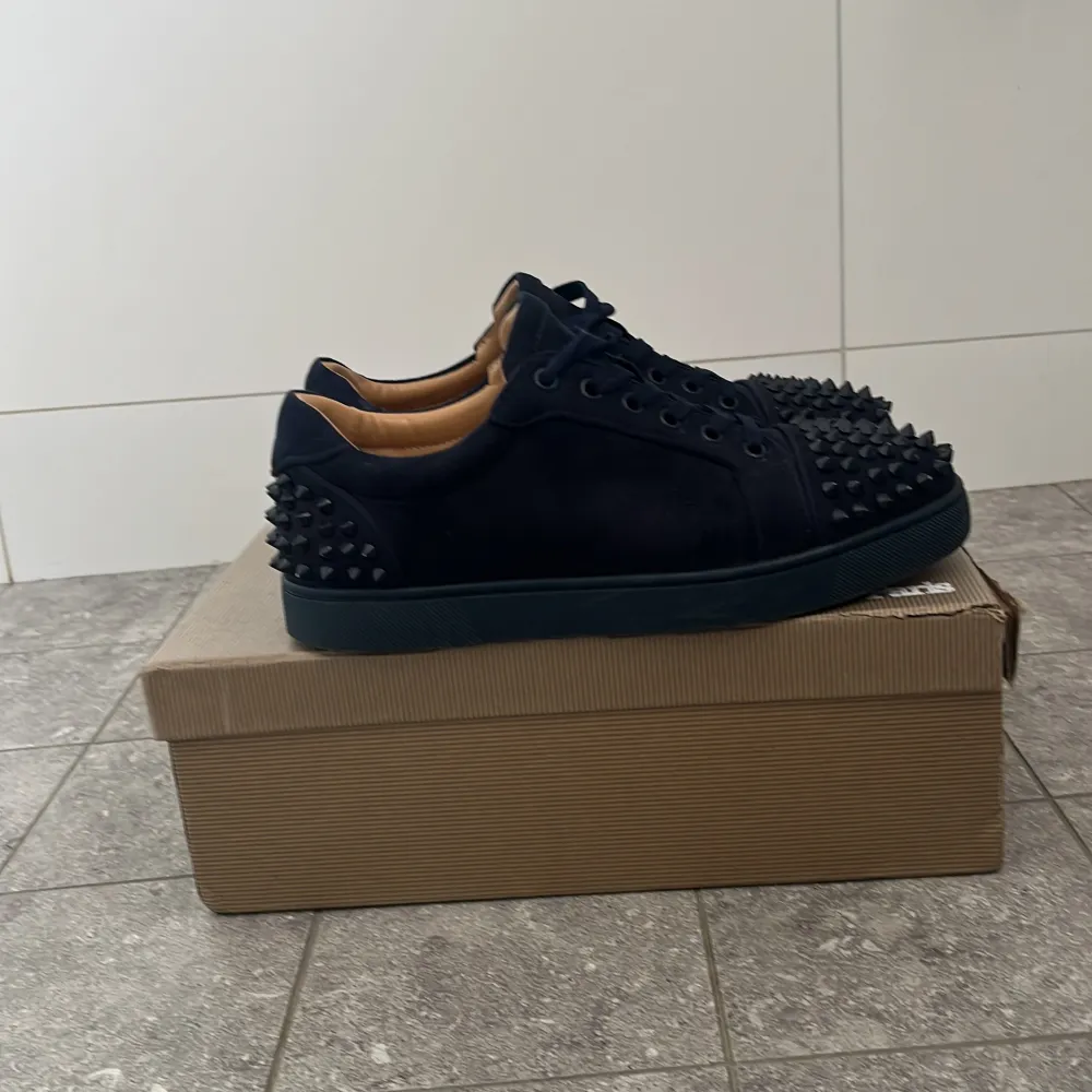 Snygga mörkblå skor från Christian Louboutin med spikar. Skorna har en ikonisk röd sula och är tillverkade i skinn. Perfekta för att ge din outfit en edgy touch.. Kengät.