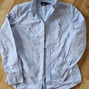  skjorta från Ralph Lauren - Säljer en klassisk ljusblå skjorta från Ralph Lauren med broderad logga på bröstet. 