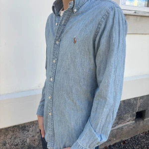 Polo Ralph Lauren skjorta - Säljer en stilren blå skjorta från Ralph Lauren. Skjortan har en slim fit passform och är dekorerad med en broderad logotyp på bröstet. Sprillans ny och pris kan diskuteras.