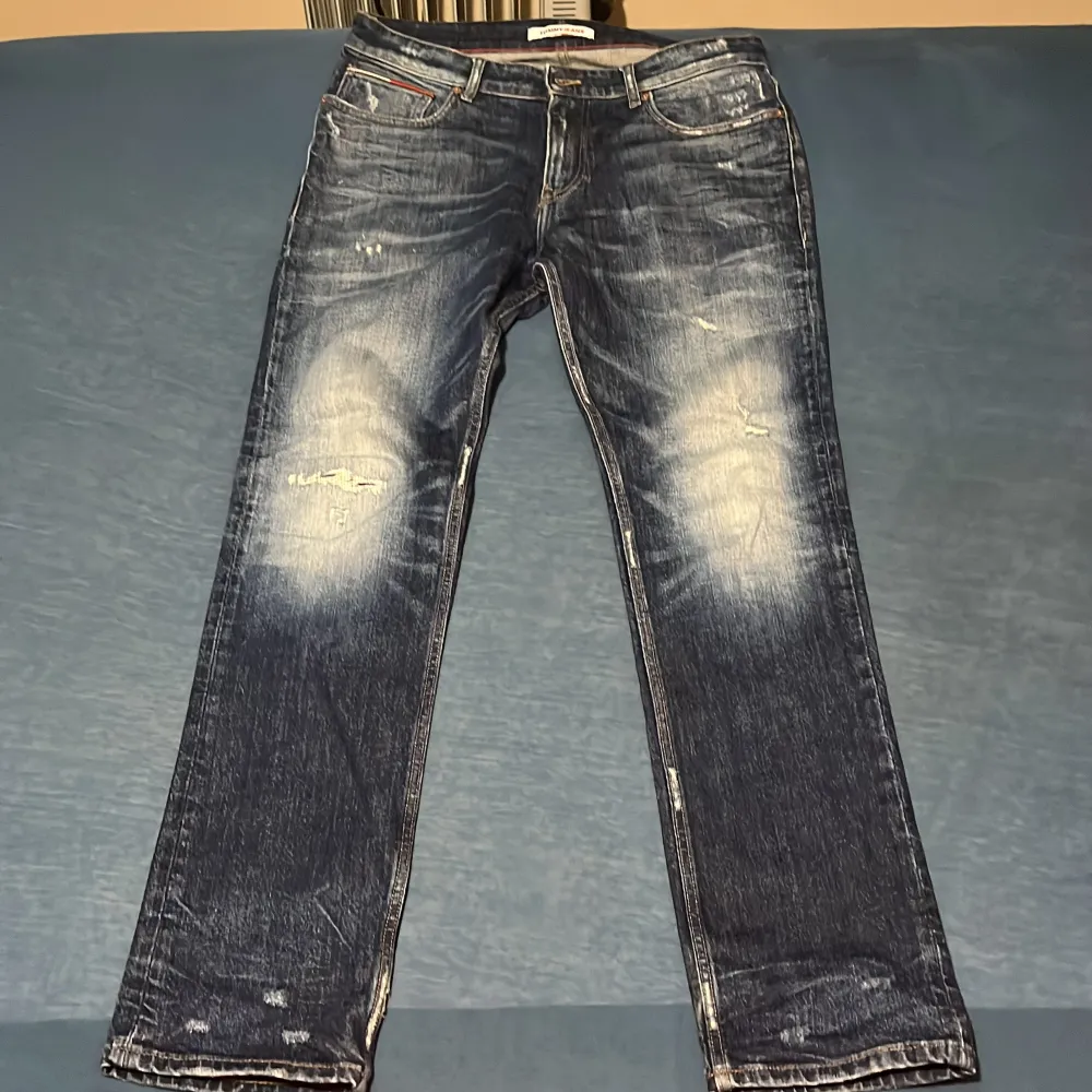 Snygga blå jeans från Tommy Hilfiger med en klassisk straight fit. De har en lätt slitning på framsidan och en läderpatch med logga på baksidan. Perfekta för en avslappnad stil. 32 i längd och bred . Farkut & Housut.